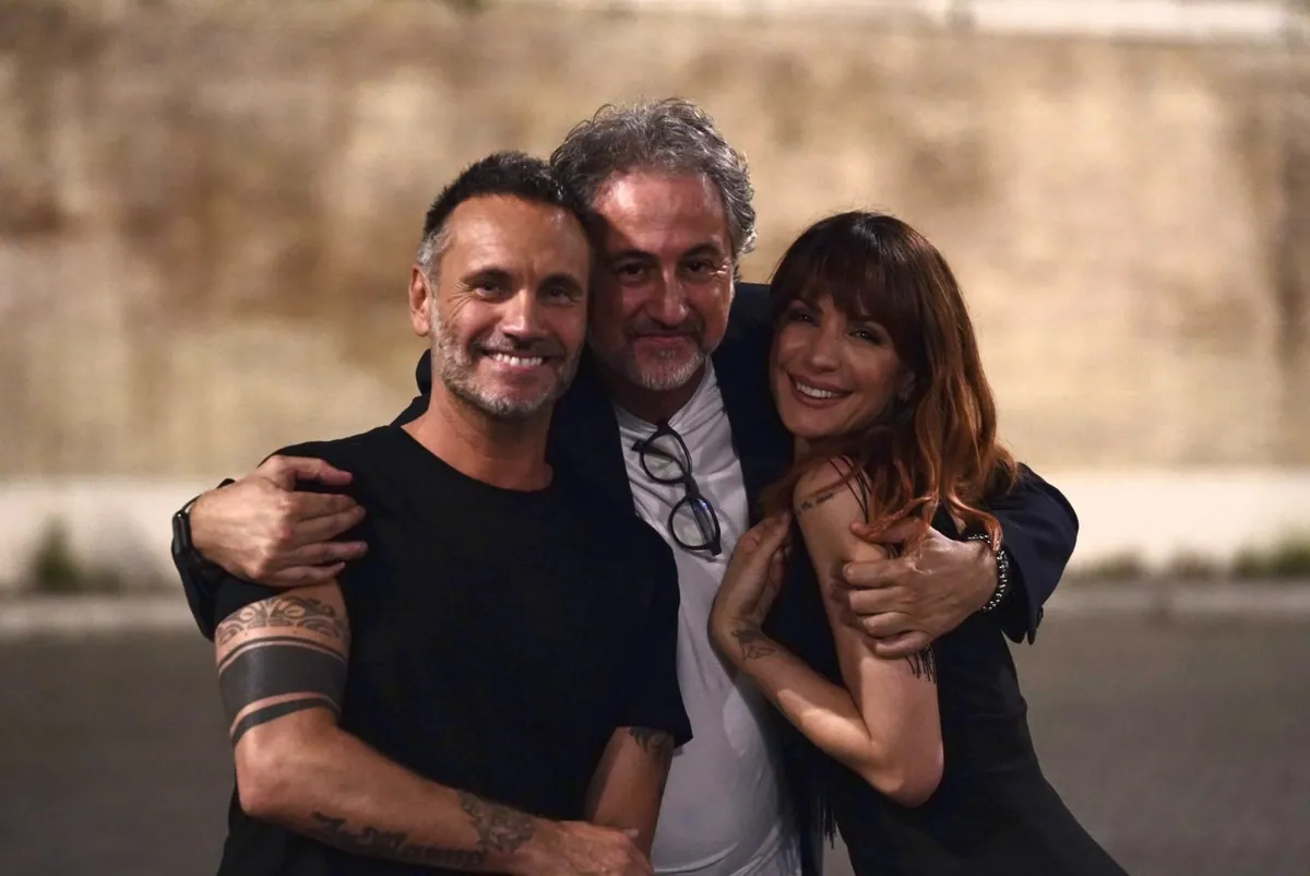 Alfonso Paoletta abbracciato a due artisti