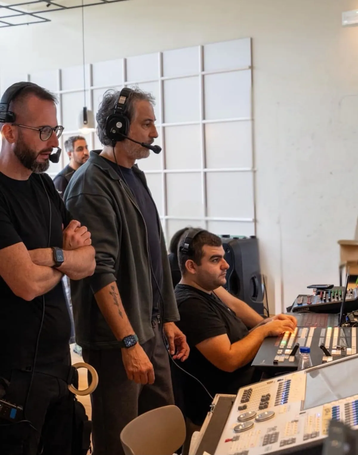 Alfonso Paoletta in piedi in regia con la squadra, con le cuffie